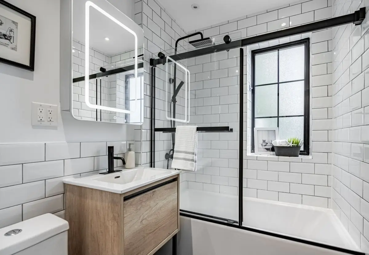 Bathroom with a black-framed shower and wood vanity