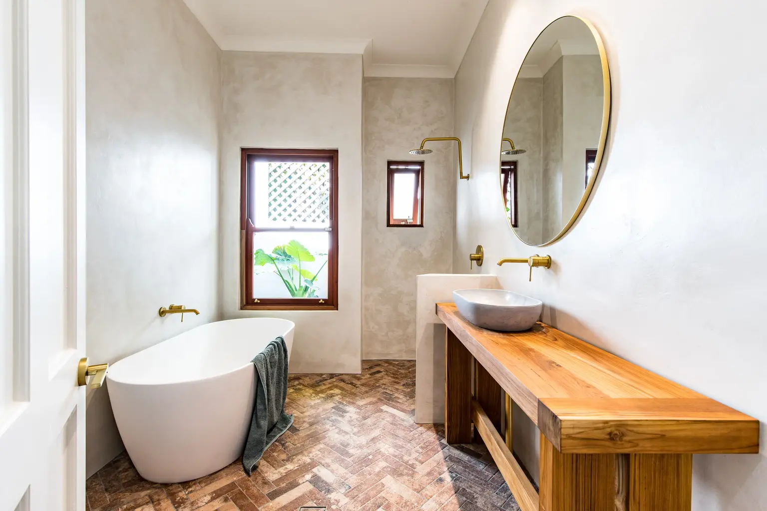 Bathroom with a freestanding tub, wood vanity and round mirror