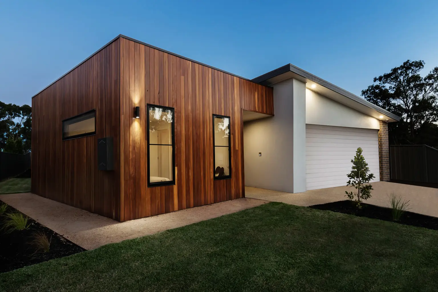 Wood-clad laneway house with a garage at dusk